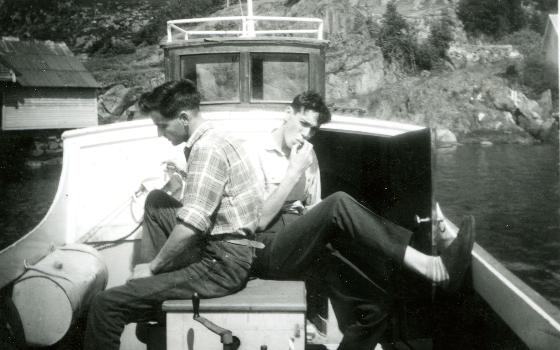 Old black and white photo of two men sitting in a boat Old black and white photo of two men sitting in a boat